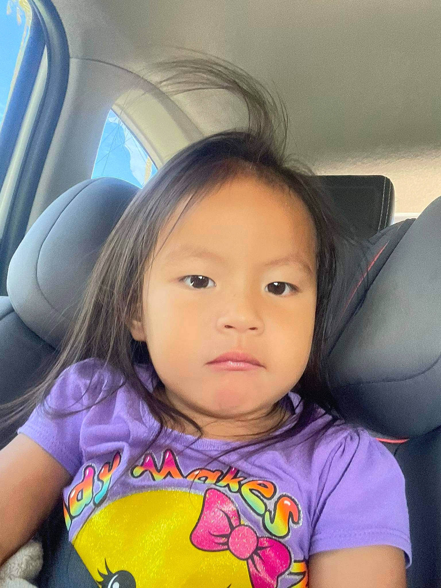 Riley participe au concours pour gagner de l'argent avec cette photo : automotive_exterior, black_hair, car_seat, car_seat_cover, cheek, cool, eyelash, happy, head_restraint, lip, mouth, nose, person, skin, steering_wheel, tints_and_shades, toddler, travel, vehicle_door, white