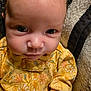 baby, infant, face, yellow_clothing, floral_pattern, blanket, closeup, child, person, cute, newborn, portrait, skin, eyes, expression, young, sleepwear, soft, texture, cozy