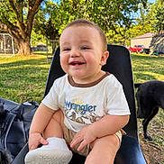 Bayler is registered to the contest to win money with this photo: baby, child, smiling, sitting, portrait, outdoor, backyard, tree, grass, dog, pet, stroller, sneaker, white_shirt, clothing, sunlight, chair, nature, happy, face