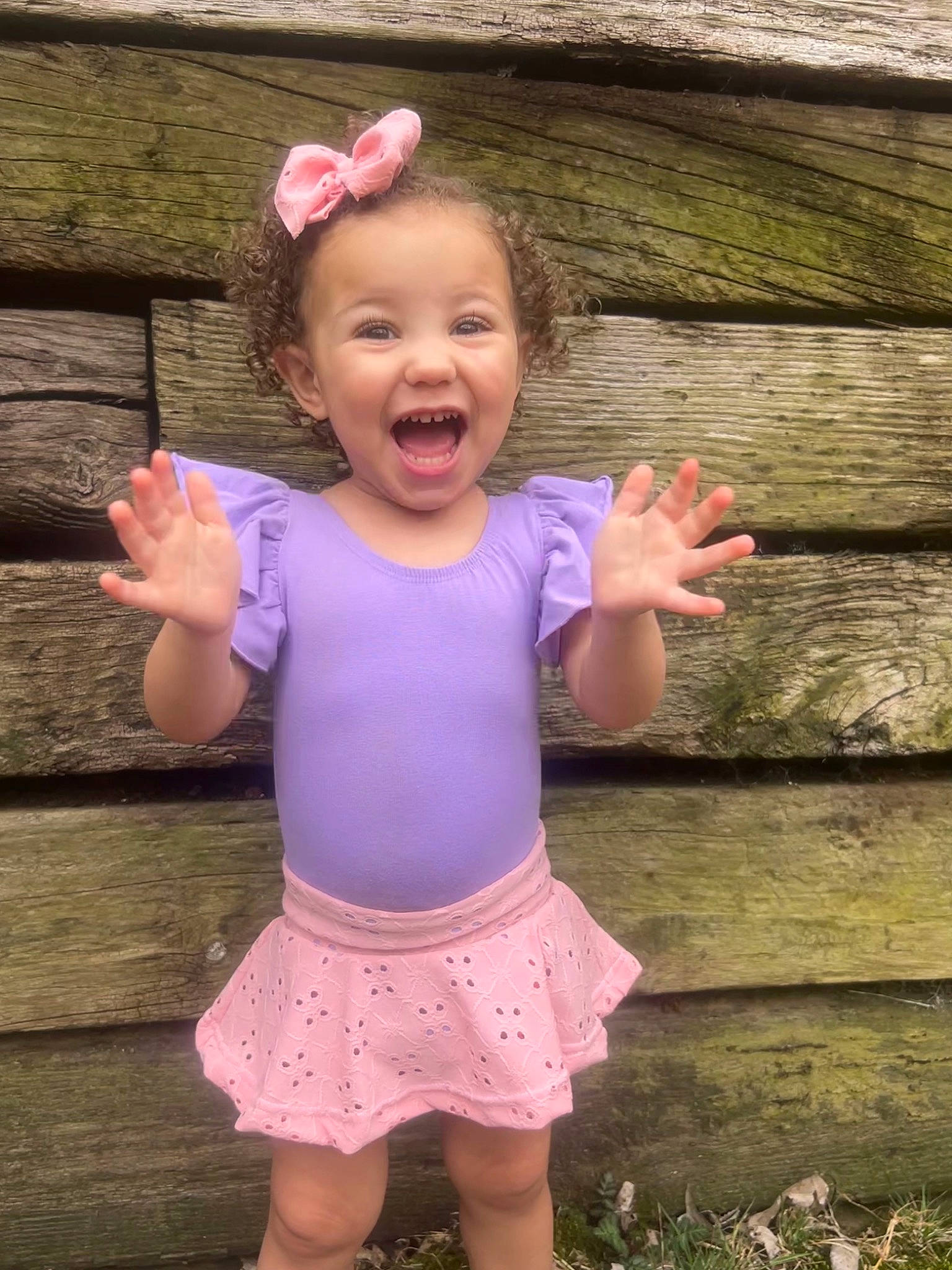 Jesslyn is registered to the contest to win money with this photo: baby_toddler_clothing, clothing, face, finger, gesture, grass, happy, head, human_body, people_in_nature, person, photograph, pink, plant, shoulder, skin, sleeve, smile, standing, toddler