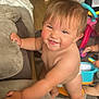 baby, toddler, smiling, indoor, living_room, couch, toy, playtime, child, diaper, barefoot, floor, carpet, furniture, happy, cute, person, hand, foot, play