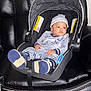 baby, blue_outfit, car_seat, child, clothing, comfort, cute, footwear, hat, indoor, infant, leather_couch, person, portrait, relaxed, seatbelt, sitting, striped, warning_label, young_child