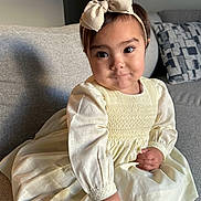Lia is registered to the contest to win money with this photo: toddler, child, girl, dress, headband, bow, bracelet, couch, sofa, living_room, indoors, cute, smiling, portrait, person, young_child, fashion, seated, hand, expression