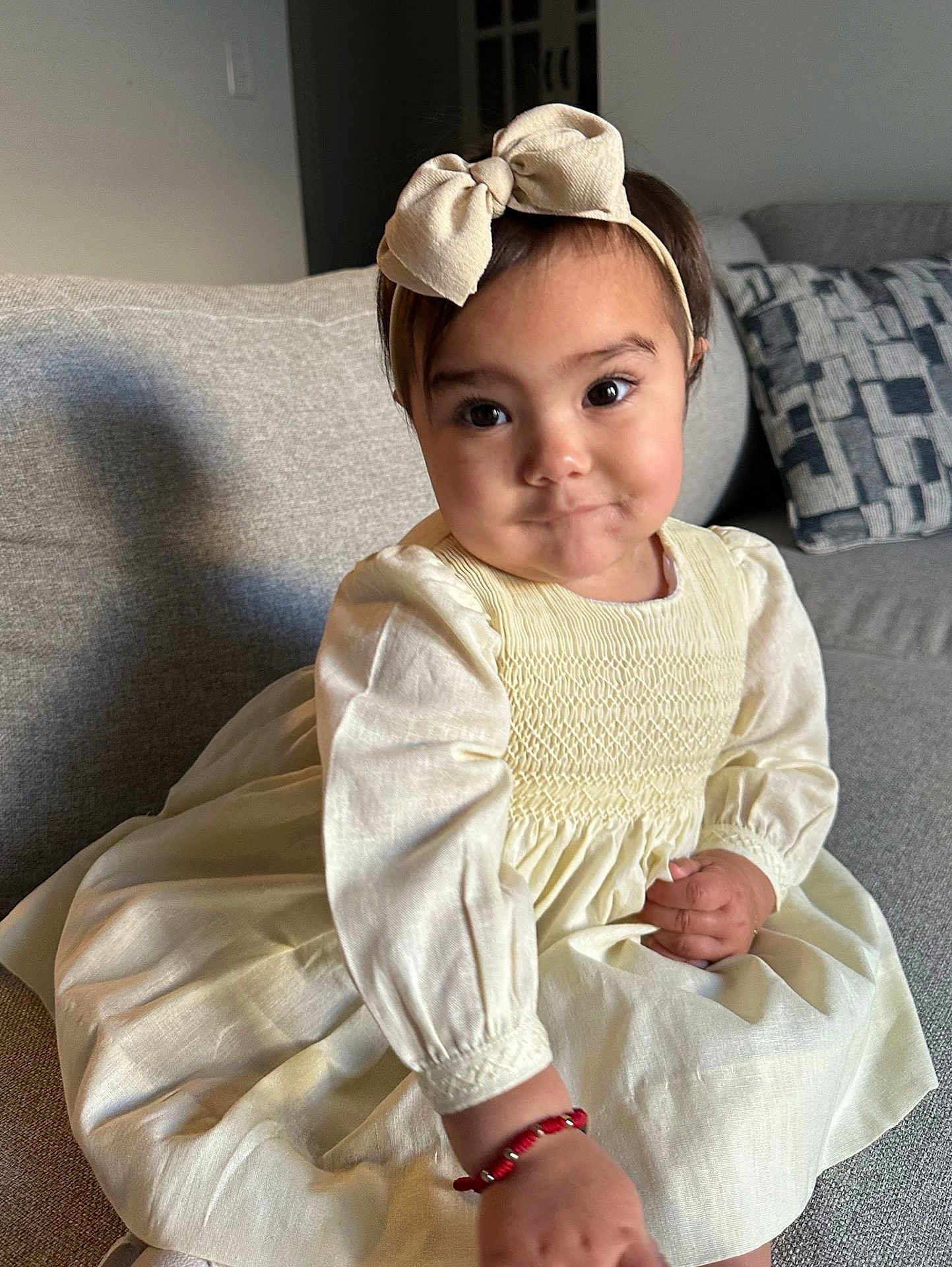 Lia is registered to the contest to win money with this photo: toddler, child, girl, dress, headband, bow, bracelet, couch, sofa, living_room, indoors, cute, smiling, portrait, person, young_child, fashion, seated, hand, expression