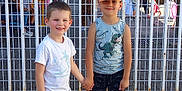 Taim participe au concours pour gagner de l'argent avec cette photo : child, boy, smiling, holding_hands, outdoor, fence, cap, tshirt, shorts, dinosaur_print, sunny, people, background, happy, casual_clothing, summer, friends, playful, portrait, street
