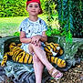 Taim a rejoint le concours — aidez-le/la à gagner de superbes lots ! child, red_cap, plush_tiger, stone_bench, outdoor, greenery, grass, gravel, leaves, summer, casual_clothing, sandals, crossed_legs, shade, nature, garden, young_person, sitting, relaxed, daylight