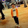 Taim a rejoint le concours — aidez-le/la à gagner de superbes lots ! child, boy, smiling, orange_jacket, white_shoes, indoor, event, people, stage, lights, floor, casual, crowd, barrier, technology, screen, happy, young, person, photography