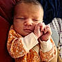 baby, newborn, sleeping, hands, face, orange_clothing, floral_pattern, cozy, infant, person, soft_fabric, closeup, cute, peaceful, tender, resting, skin, portrait, child, warm