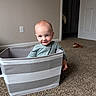 toddler, child, storage_bin, carpet, indoor, smile, playful, toy, plush_toy, striped, fabric, room, door, wall, light_switch, hand, head, face, blue_eyes, casual_clothing