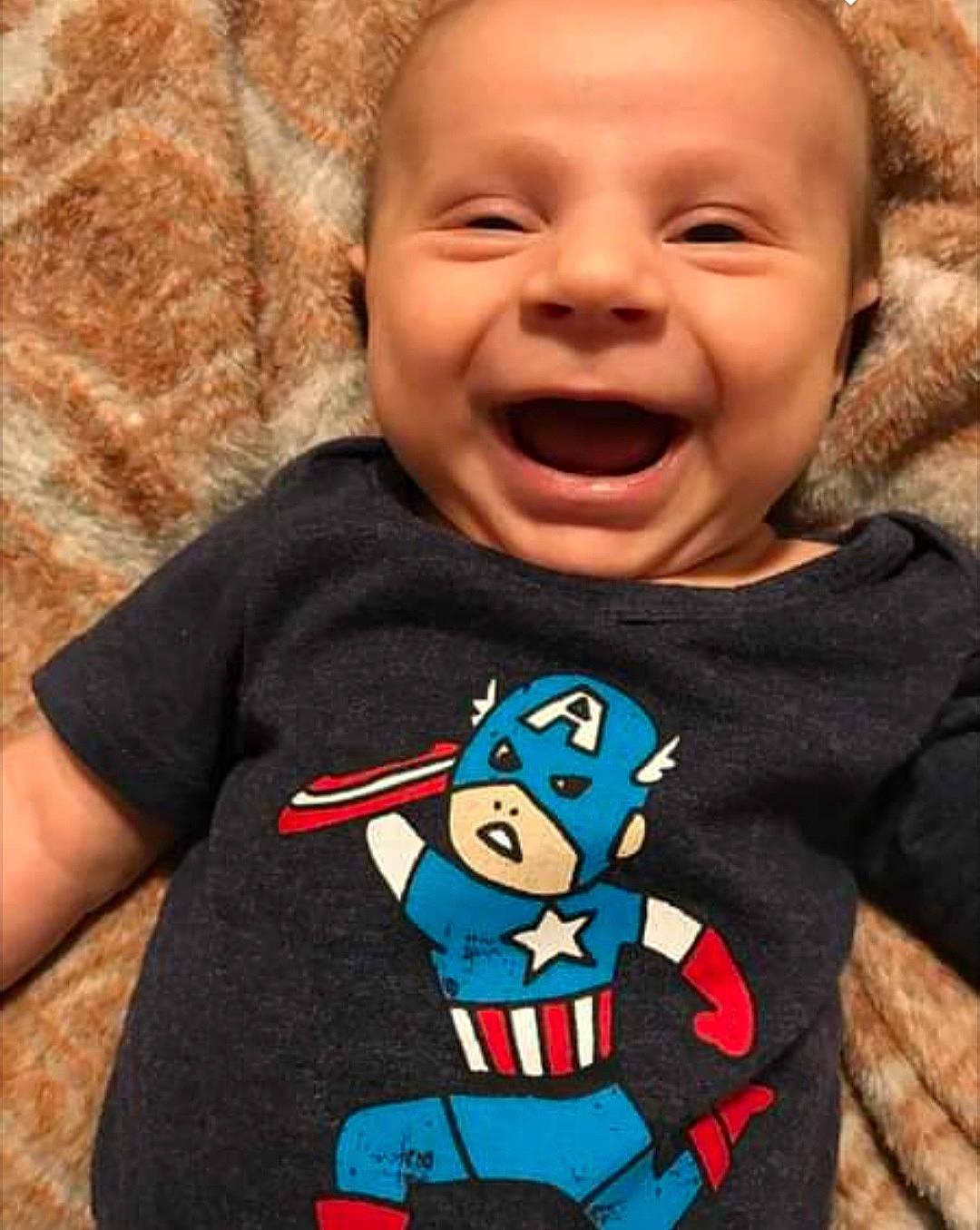 Bennett is registered to the contest to win money with this photo: arm, baby_toddler_clothing, cheek, chin, face, facial_expression, gesture, happy, head, human_body, mouth, neck, nose, organ, outerwear, person, sleeve, smile, standing, t_shirt