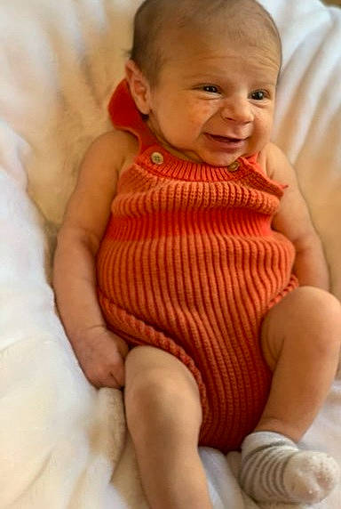 Bennett is registered to the contest to win money with this photo: baby, baby_toddler_clothing, comfort, dress, eye, gesture, happy, knee, lip, neck, nose, person, pink, skin, sleeve, smile, stomach, textile, thigh, thumb