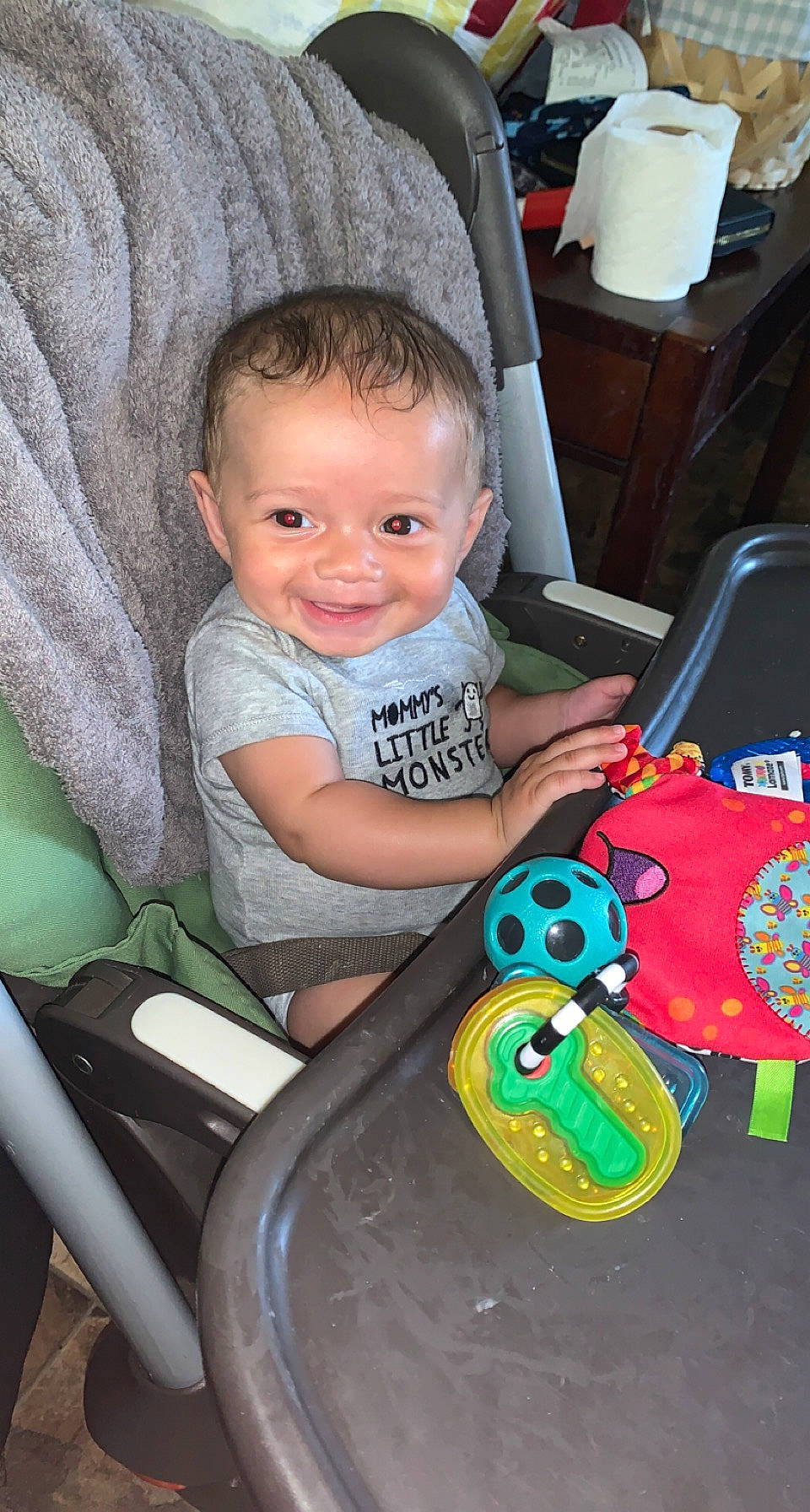 Elijah is registered to the contest to win money with this photo: baby, baby_products, baby_toddler_clothing, chair, child, comfort, fun, hairstyle, happy, head, input_device, iris, joy, lap, person, sitting, smile, standing, t_shirt, toddler
