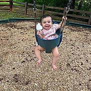 Kamayah joined the competition — help win amazing prizes! baby, swing, playground, child, smiling, happy, outdoor, woodchips, greenery, tree, fence, clothing, person, seat, fun, nature, toy, baby_clothes, summer, park