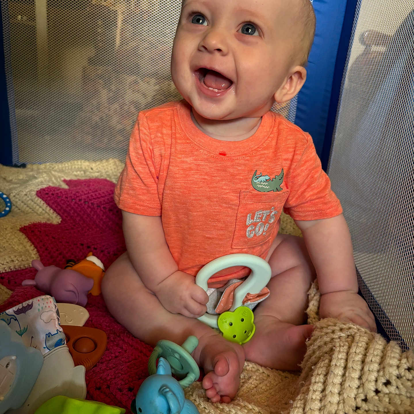 Jebediah joined the competition — help win amazing prizes! baby, blue_toy, cheerful, child, crawling, cute, face, green_toy, hand, happy, indoors, infant, knit_blanket, orange_shirt, playpen, playtime, purple_toy, sitting, smiling, toys