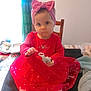 child, toddler, baby, pink_headband, bow, red_dress, sitting, chair, toy, indoor, curtain, window, portrait_photo, table, shoes, socks, blanket, hand, face, cute