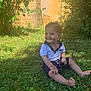 toddler, child, grass, outdoor, greenery, smile, happy, nature, sunlight, shadow, polo_shirt, shorts, barefoot, garden, stone_wall, plant, shrub, summer, portrait, sitting