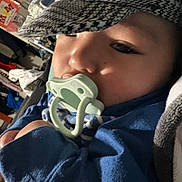 Aurelius joined the competition — help win amazing prizes! baby, pacifier, hat, blue_clothing, face, child, infant, closeup, indoors, blanket, patterned_hat, sleepy, young_child, portrait, cozy, soft_light, home, furniture, person, cute