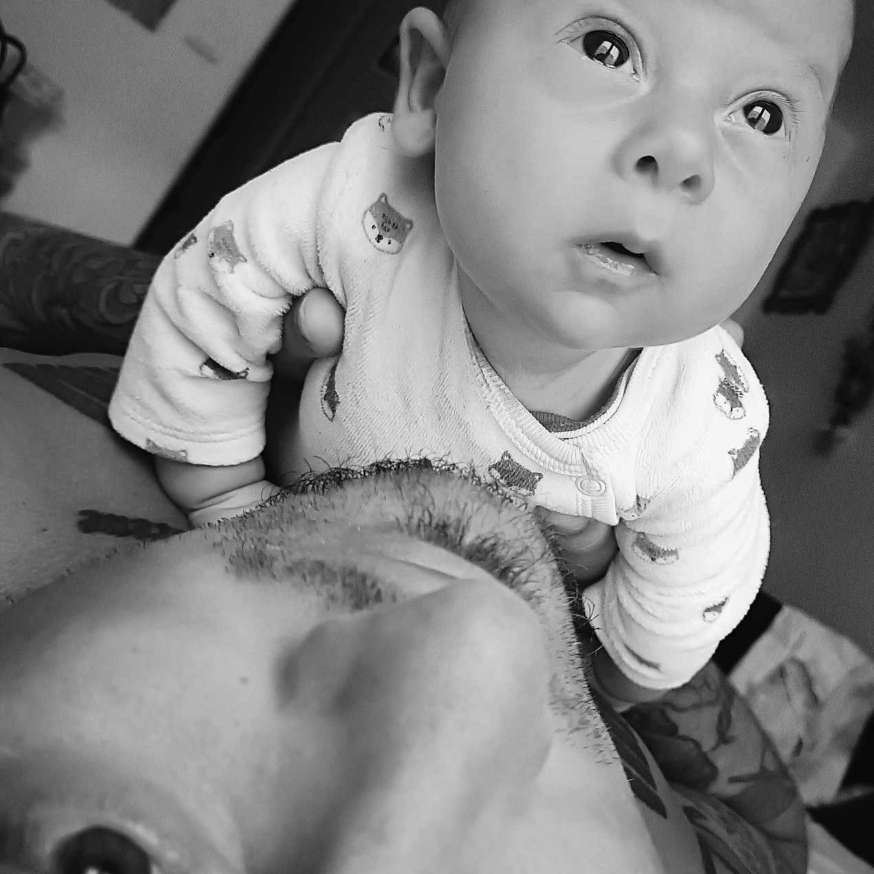 Maïwen participe au concours pour gagner de l'argent avec cette photo : adult, baby, black_and_white, bonding, close_up, clothing, curious, expression, eyes, face, family, hand, head, indoor, intimate, love, person, portrait, skin, tattoo