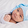 newborn, baby, infant, wrapped, blanket, blue_hat, knitted_hat, crescent_moon, face, cute, sleeping_area, soft, closeup, portrait, skin, hand, fist, lying_down, bed, cozy