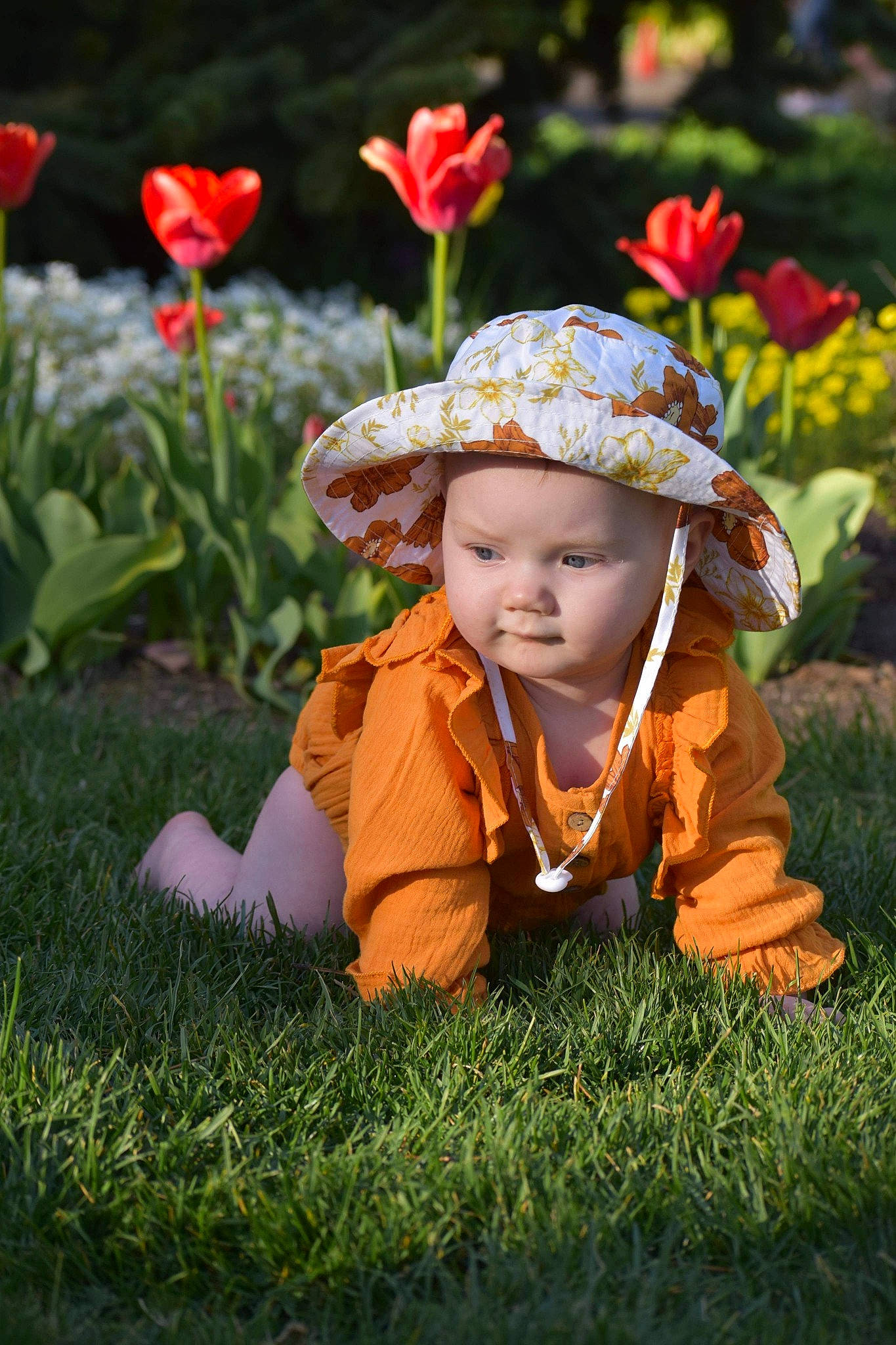Coraline is registered to the contest to win money with this photo: baby, baby_toddler_clothing, botany, eye, face, flower, fun, grass, happy, hat, head, headwear, leaf, leisure, orange, people_in_nature, person, petal, plant, sun_hat