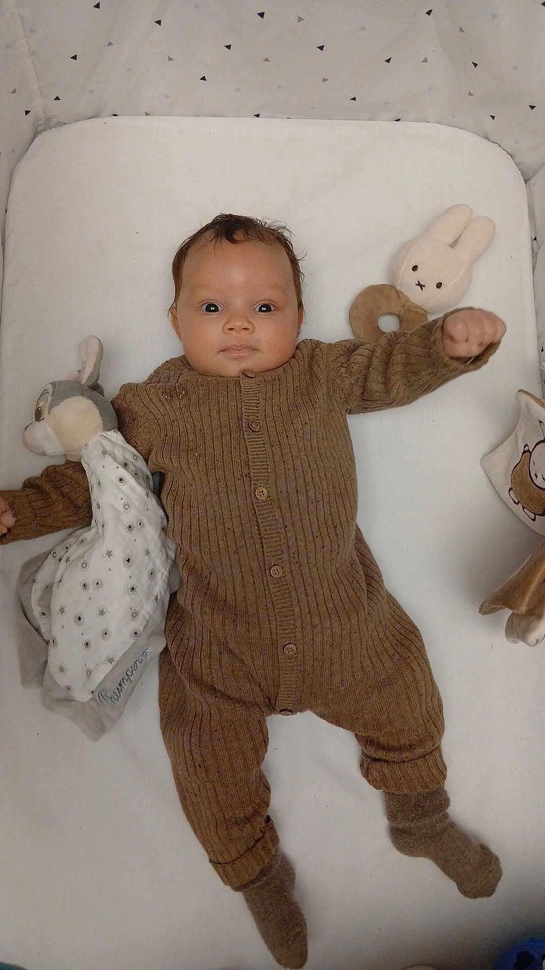 Isayah participe au concours pour gagner de l'argent avec cette photo : baby, infant, plush_toy, brown_onesie, knitted_clothing, lying_down, white_background, sock, soft_toy, stuffed_animal, face, person, cute, indoors, child, cozy, blanket, comfort, expression, hand