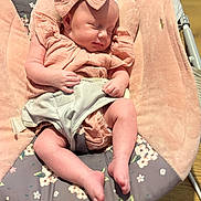 Nancy is registered to the contest to win money with this photo: baby, sleeping, bow, headband, pink_clothing, baby_rocker, floral_pattern, plush, infant, peaceful, soft_lighting, hands, legs, footwear_none, indoors, wooden_floor, comfort, child, portrait, resting