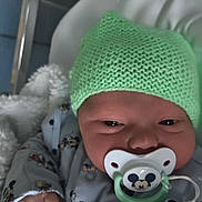 Kenzo participe au concours pour gagner de l'argent avec cette photo : baby, newborn, pacifier, mickey_mouse, hat, knit_hat, blanket, crib, infant, clothing, cute, child, sleepwear, toy, comfort, soft, warm, resting, indoors, person
