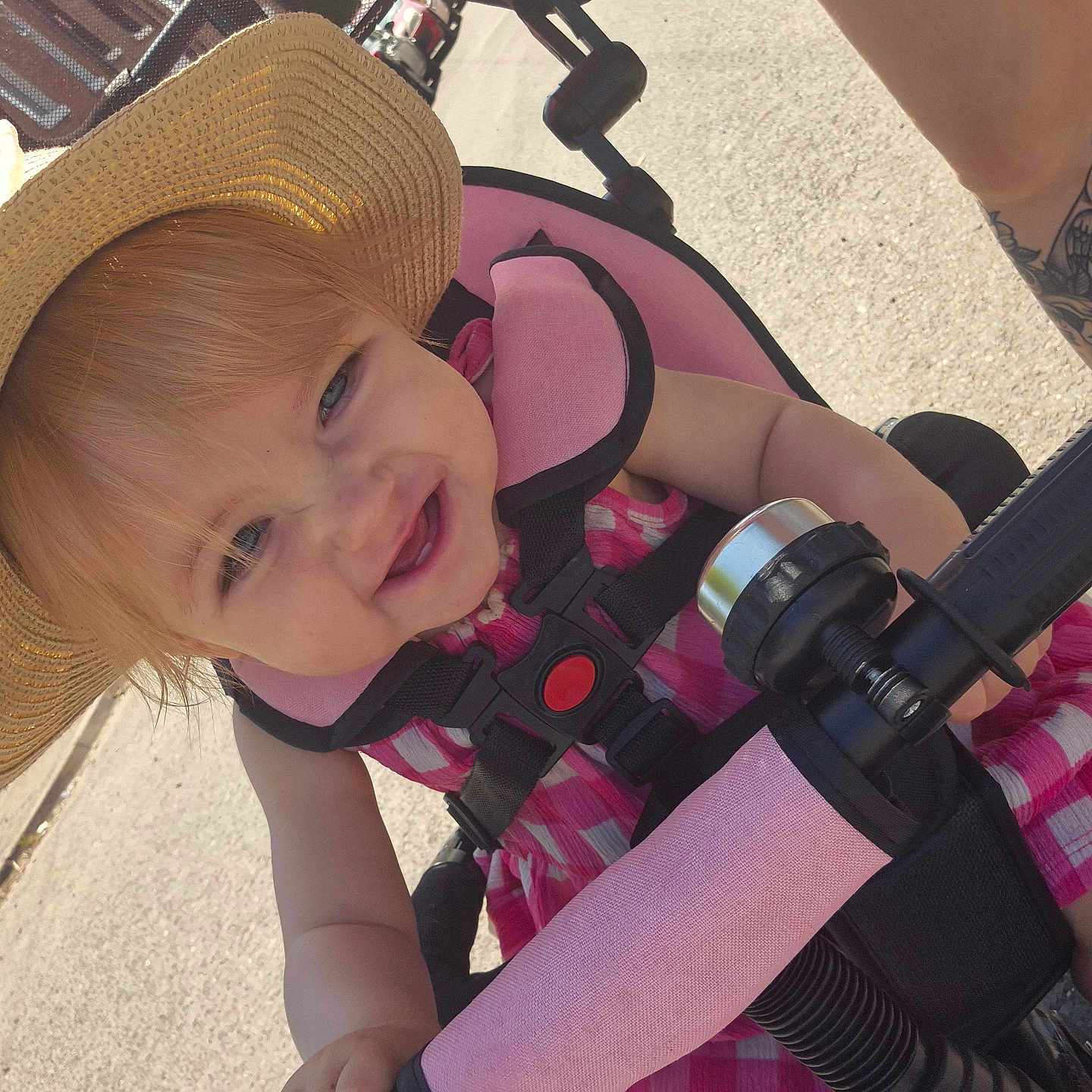 Lyanna joined the competition — help win amazing prizes! baby, child, closeup, daylight, footwear, handlebar, happy, hat, outdoor, person, pink_dress, seat_belt, sidewalk, smiling, street, stroller, summer, sun_hat, tattoo, toddler