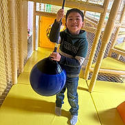 Theseus is registered to the contest to win money with this photo: child, boy, smile, indoor_playground, rope_swing, yellow_floor, netting, casual_clothing, hoodie, jeans, socks, play_area, happy, fun, active, young, person, leisure, recreation, entertainment