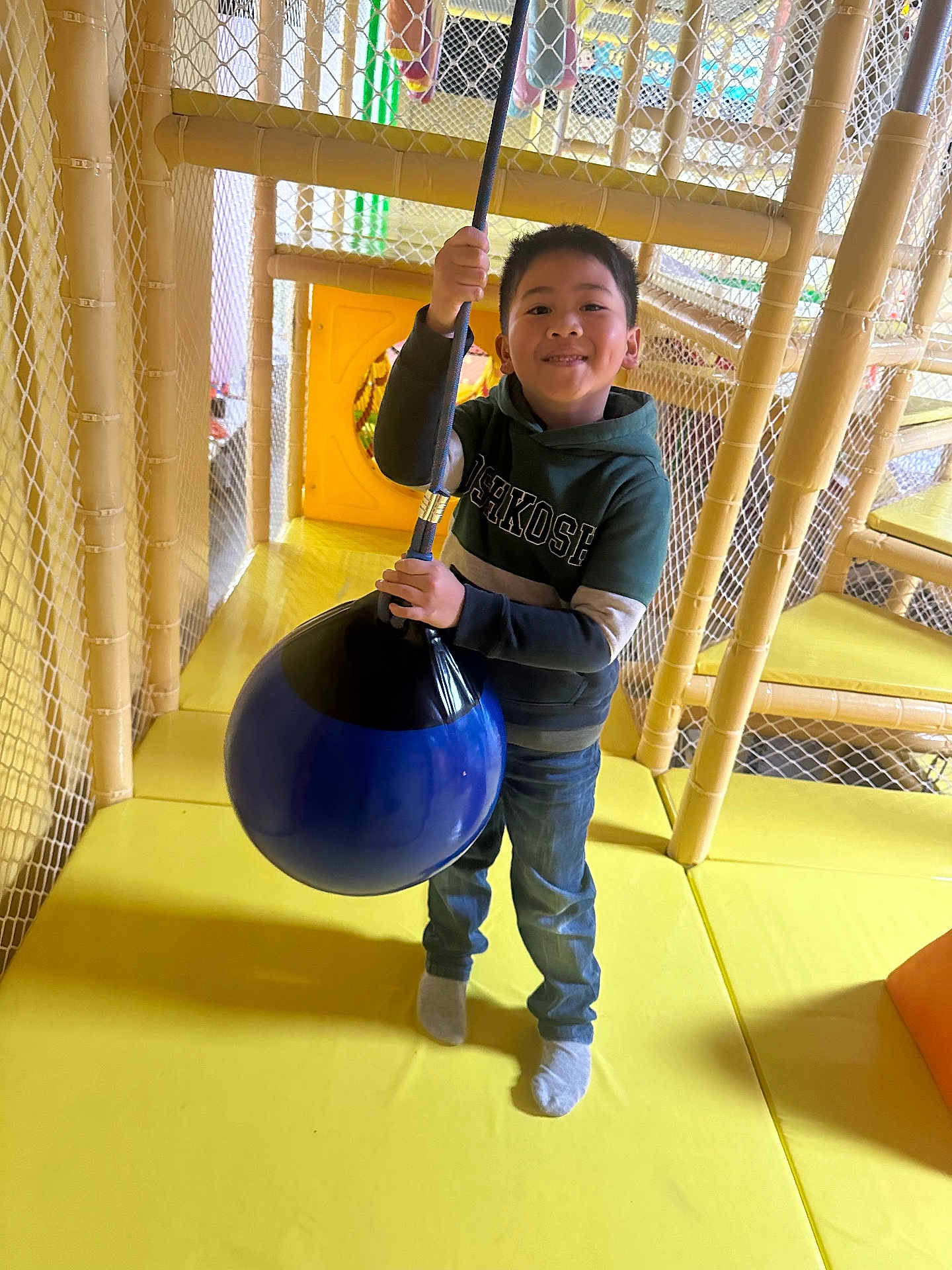 Theseus is registered to the contest to win money with this photo: child, boy, smile, indoor_playground, rope_swing, yellow_floor, netting, casual_clothing, hoodie, jeans, socks, play_area, happy, fun, active, young, person, leisure, recreation, entertainment