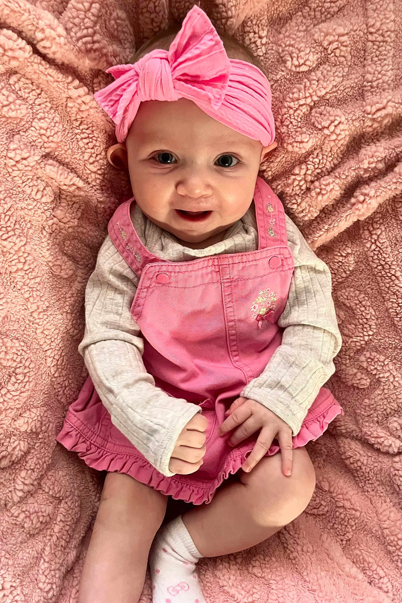 Chloe is registered to the contest to win money with this photo: baby, child, pink_headband, pink_dress, smile, happy, cute, infant, sitting, blanket, soft_texture, portrait, indoor, young_child, headwear, clothing, sock, person, closeup, baby_fashion