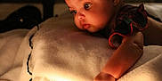 Ava is registered to the contest to win money with this photo: baby, child, red_headband, flower_headband, string_lights, blanket, soft_lighting, indoors, curious, infant, closeup, warm_tone, candid, portrait, cozy, holiday_lights, face, hand, expression, decor