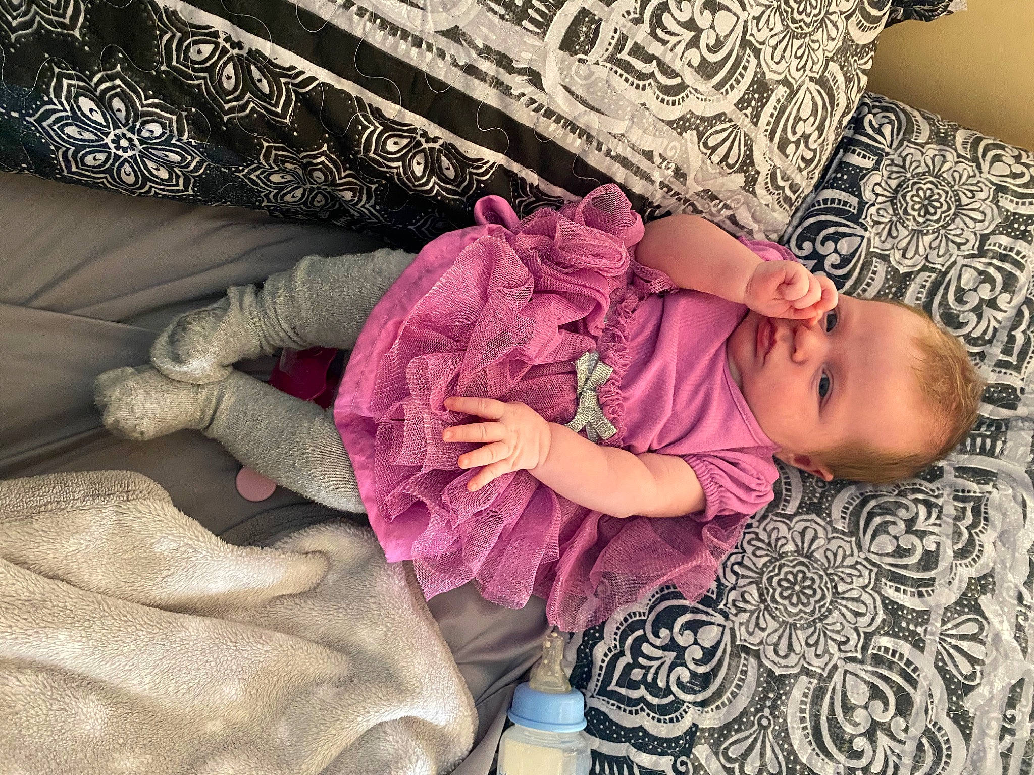 Karley is registered to the contest to win money with this photo: baby, baby_toddler_clothing, bedding, comfort, couch, finger, flooring, hand, happy, human_body, linens, magenta, pattern, person, pink, purple, room, sleeve, textile, toddler