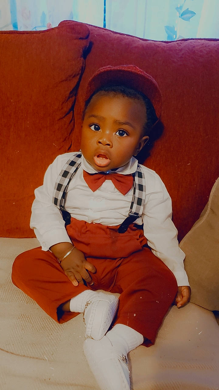 Jeremy is registered to the contest to win money with this photo: baby_toddler_clothing, brown_hair, cheek, child, comfort, doll, eye, fashion_design, happy, human_body, human_leg, peach, person, sitting, skin, sleeve, surprise, thigh, toddler, toy