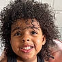 child, smiling, curly_hair, face, teeth, black_tank_top, indoor, person, portrait, happy, cute, skin, young, expression, head_and_shoulders, childhood, natural_light, casual, closeup, hair