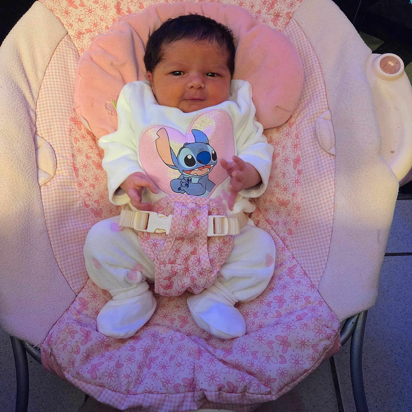 Giulia participe au concours pour gagner de l'argent avec cette photo : baby, baby_rocker, child, comfort, curious, cute, feet, floor, floral_pattern, hands, indoor, infant, newborn, pajamas, pink, portrait, seat_belt, soft, stitch_character, white_clothing