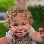 Axel is registered to the contest to win money with this photo: baby, casual_clothing, child, closeup, curly_hair, cute, daylight, face, fun, grass, happy, nature, outdoor, person, playful, portrait, reaching, smiling, toddler, young