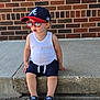 Axel is registered to the contest to win money with this photo: brick_wall, cap, casual, child, concrete, cool, fashion, hat, outdoor, person, shoes, shorts, sidewalk, sitting, street_style, summer, sunglasses, toddler, white_tank_top, young_child