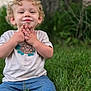 casual_clothing, child, curly_hair, cute, daylight, denim_shorts, grass, greenery, happy, nature, outdoor, person, playful, portrait, sitting, smiling, toddler, tree, tshirt, young_child