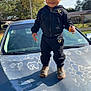 clothing, pants, face, head, person, photography, portrait, coat, jacket, footwear, shoe, bodypart, finger, hand, jeans, boy, child, male, car, transportation