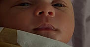 Darvy Domingos Veiga is registered to the contest to win money with this photo: baby, bed, blanket, child, close_up, cozy, eyes, face, head, home, indoors, infant, mouth, newborn, nose, patterned_fabric, photography, portrait, sleepy, swaddled