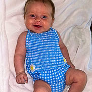 Livvy joined the competition — help win amazing prizes! baby, infant, smiling, blue_outfit, checkered_pattern, daisy, blanket, soft_texture, cute, happy, child, skin, legs, arms, head, face, indoors, portrait, sitting, comfort