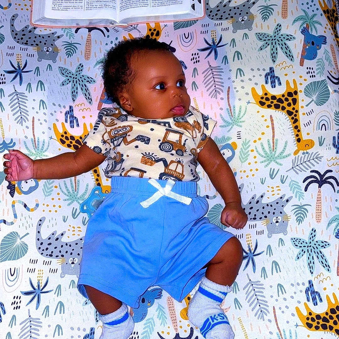 Aleric joined the competition — help win amazing prizes! animal_print, baby, blanket, blue_shorts, book, child, colorful, curious, cute, elephant, giraffe, indoor, infant, lying_down, open_book, patterned_socks, plants, playful, soft_lighting, young_child