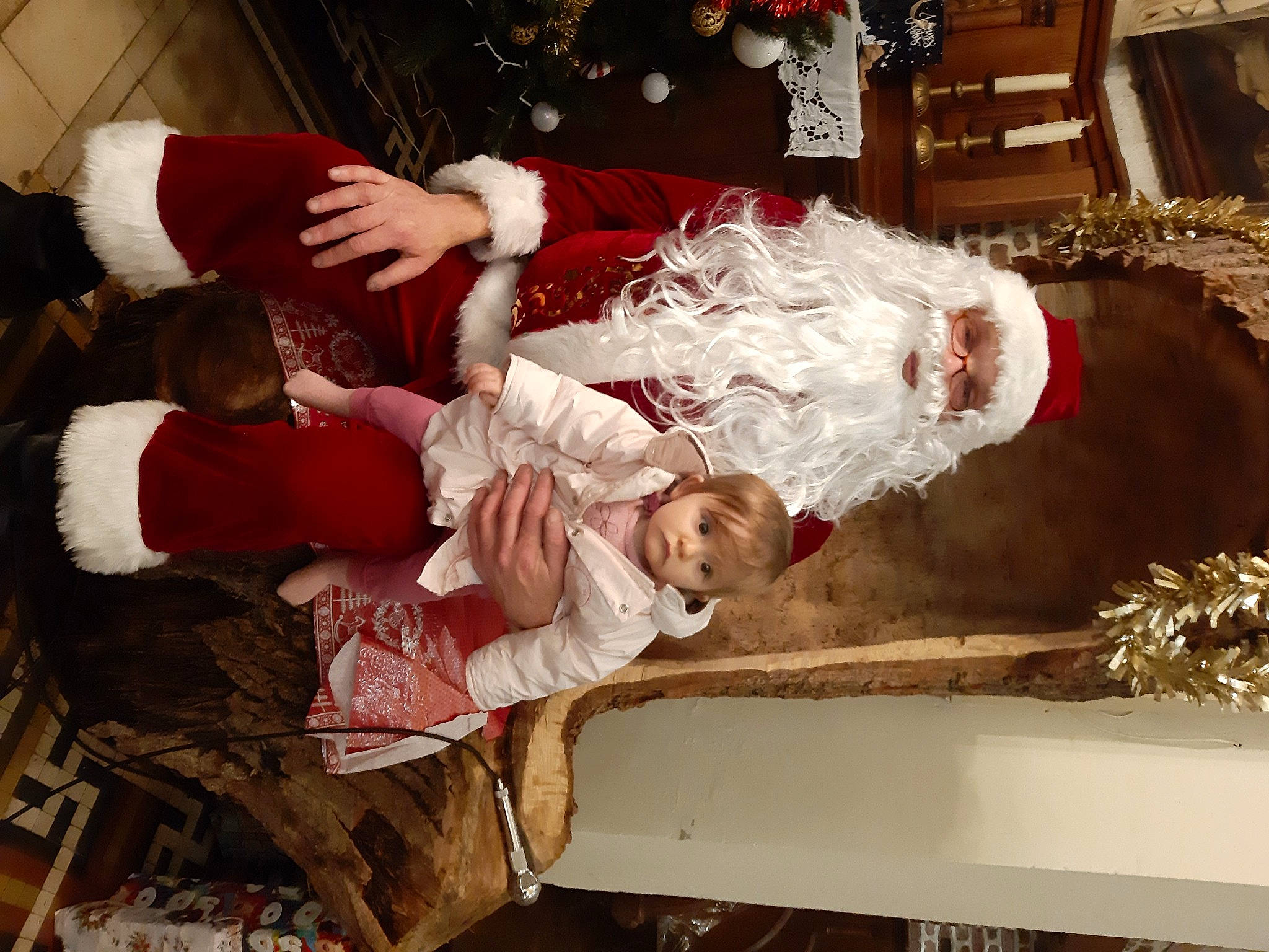 Nina participe au concours pour gagner de l'argent avec cette photo : baby, carmine, child, christmas, christmas_decoration, christmas_eve, christmas_tree, comfort, dress, event, fun, happy, headwear, holiday, interior_design, lap, person, room, sitting, toddler