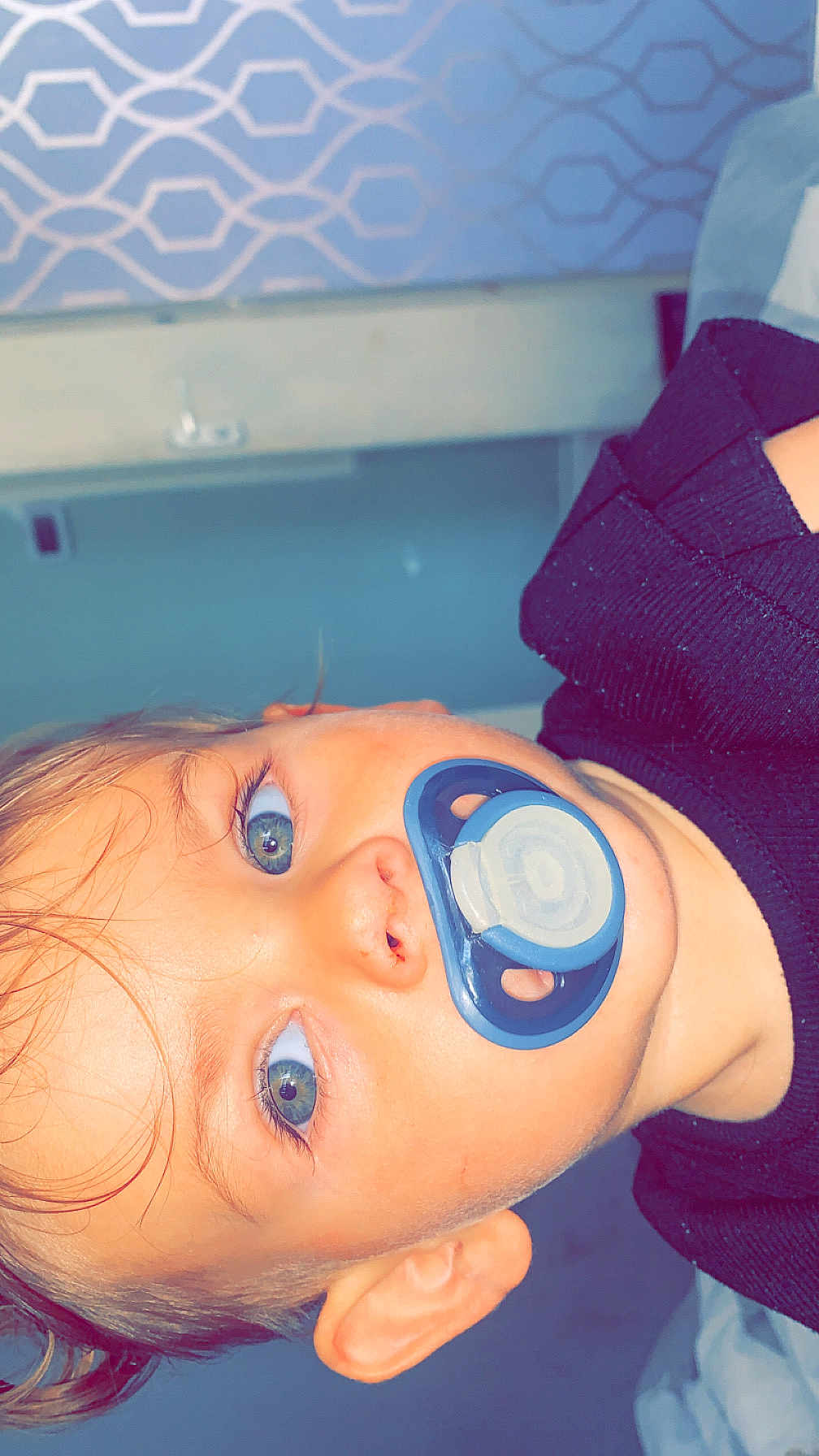 Bonnie-Rae joined the competition — help win amazing prizes! baby, pacifier, blue_eyes, face, child, infant, close_up, indoors, bed, blanket, sweater, person, skin, head, ear, nose, mouth, hair, patterned_wall, resting