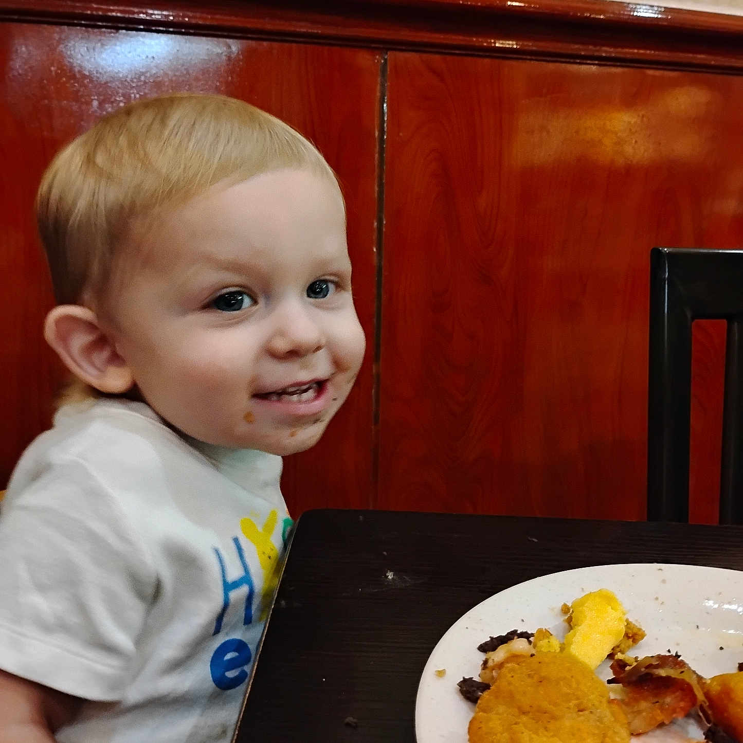 Daxton Kole joined the competition — help win amazing prizes! chair, child, clothing, cute, eating, face, food, fried_food, happy, indoor, meal, messy, person, plate, portrait, smile, table, toddler, white_shirt, wood_paneling