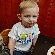 Daxton Kole joined the competition — help win amazing prizes! boy, casual_clothing, chair, child, curious_expression, easter, family, food, happy_easter_shirt, indoor, meal, messy_face, person, plate, portrait, short_blond_hair, sitting, table, toddler, wooden_background