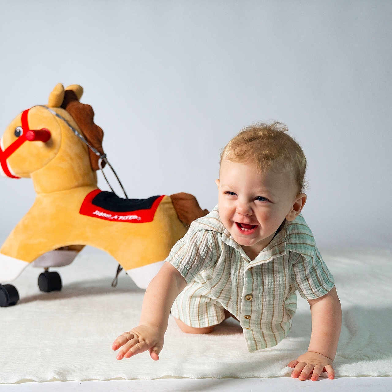 Wrenlen is registered to the contest to win money with this photo: baby, child, childhood, clothing, crawling, cute, happy, indoor, infant, light_background, person, playtime, plush_toy, portrait, rocking_horse, small_child, smiling, soft_toy, toy, white_rug