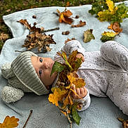 Arlo joined the competition — help win amazing prizes! baby, child, blanket, autumn, leaves, hat, knit_hat, pajamas, outdoor, grass, fall, nature, infant, cute, toddler, branch, lying_down, seasonal, leaf, soft_texture
