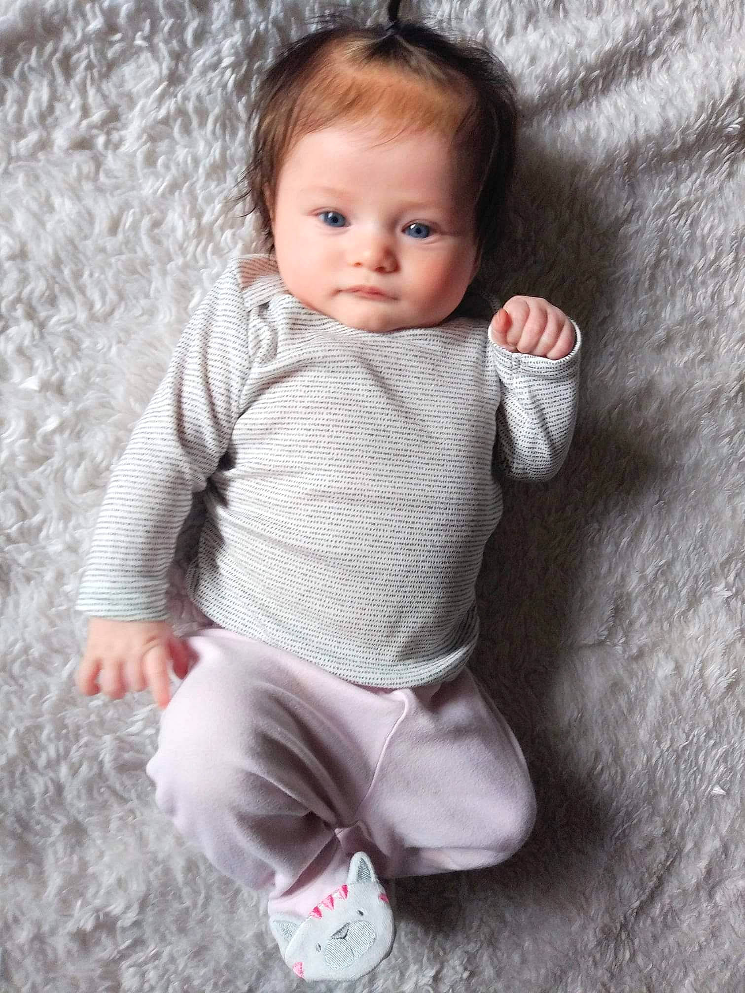 Milli is registered to the contest to win money with this photo: baby, baby_products, baby_toddler_clothing, brown_hair, cheek, child, child_model, pattern, person, photography, pink, portrait, portrait_photography, product, sitting, skin, sleeve, smile, toddler, wool
